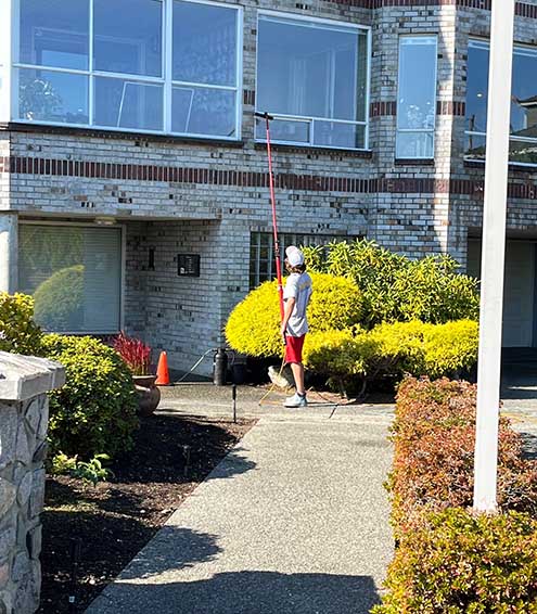 A staff of Mr. Sparkle Exterior Cleaning as he cleans an exterior window.